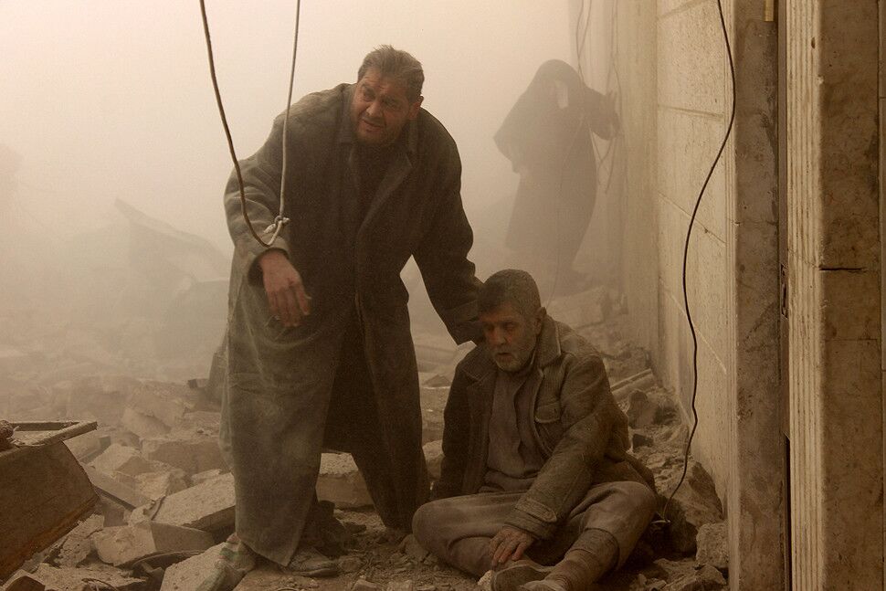 A Syrian man helps an injured resident following an airstrike in Aleppo's Maadi neighborhood.