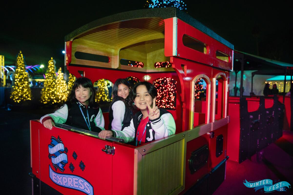 Kids pose for a photo before riding a trolley at Winter Fest OC.