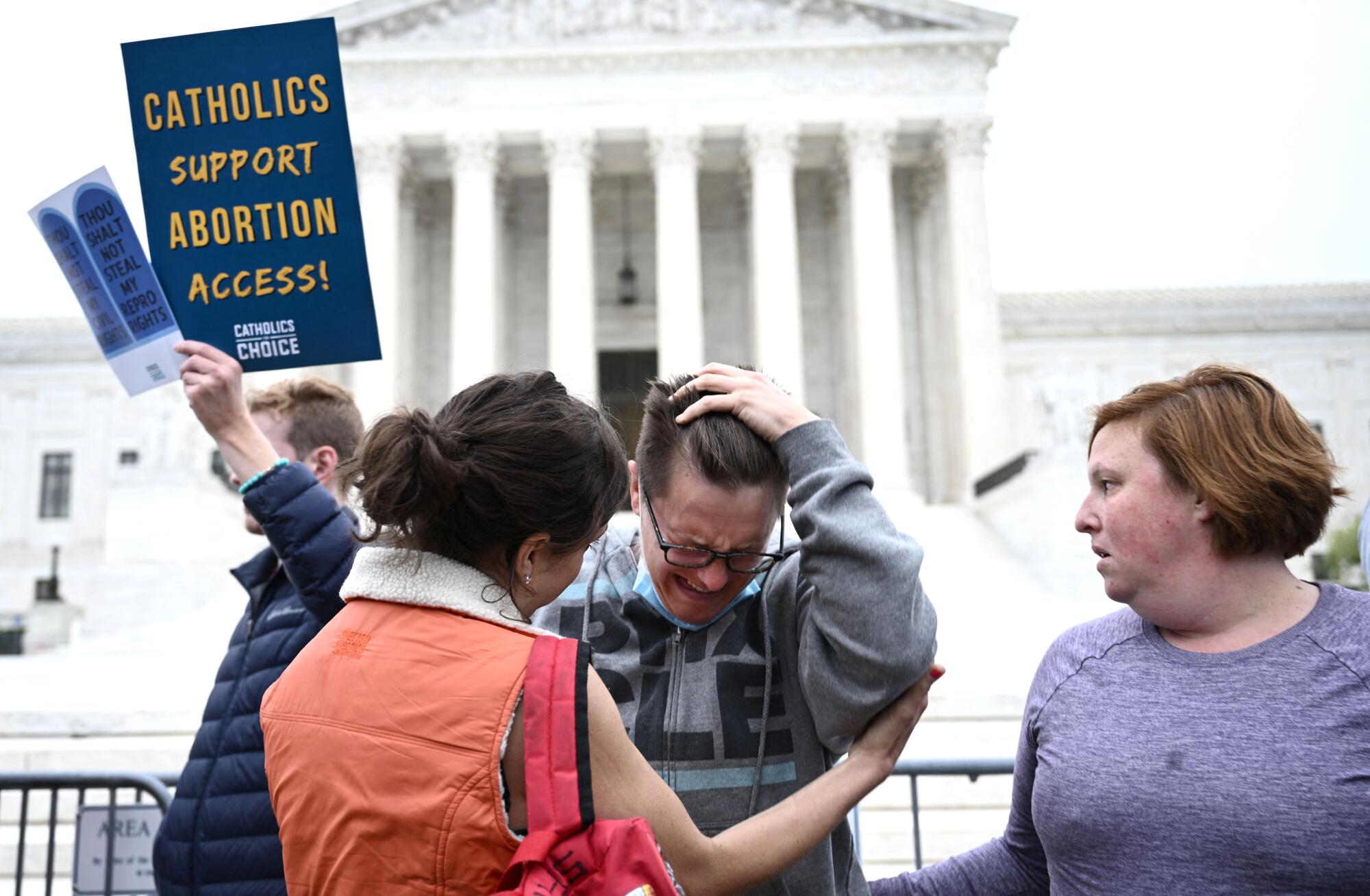 A woman pulls back her hair as she cries.