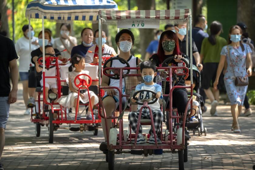 Adults and children ride pedal cycles at a public park in Beijing, Saturday, Aug. 21, 2021. China will now allow couples to have a third child as the country seeks to hold off a demographic crisis that threatens its hopes of increased prosperity and global influence. (AP Photo/Mark Schiefelbein)