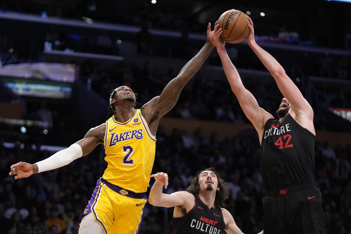 Lakers forward Jarred Vanderbilt and Miami Heat forward Kevin Love reach for a rebound.