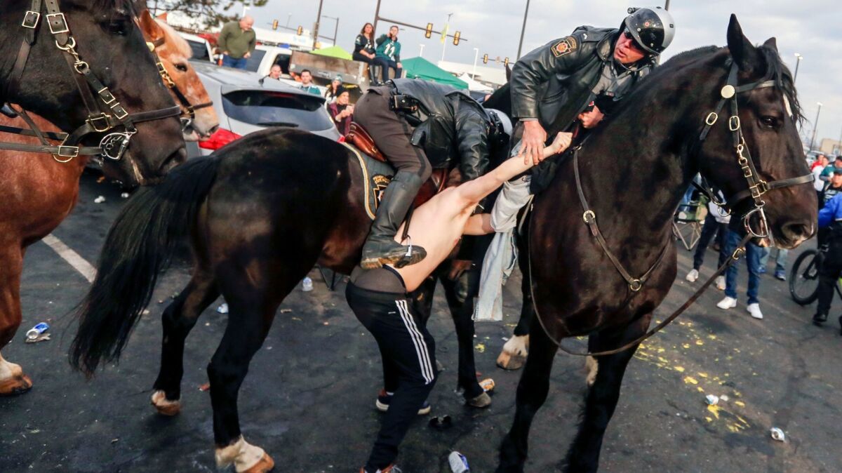 A fan is taken into custody in Lincoln Financial Field's Parking Lot M as Philadelphia Police and Pennsylvania State Troopers on horseback tried to disperse fans who were tailgating hours before the Eagles-Minnesota Vikings game on Jan. 21.