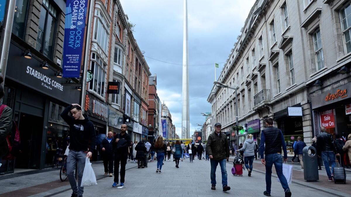 Pedestrians at the corner of O’Connell Street and Henry Street in Dublin, where a stainless steel tower known as the Spire of Dublin reaches 390 feet into the sky.