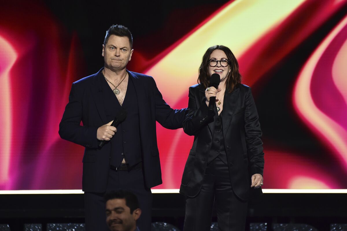 A man and a woman speak onstage at an awards show.