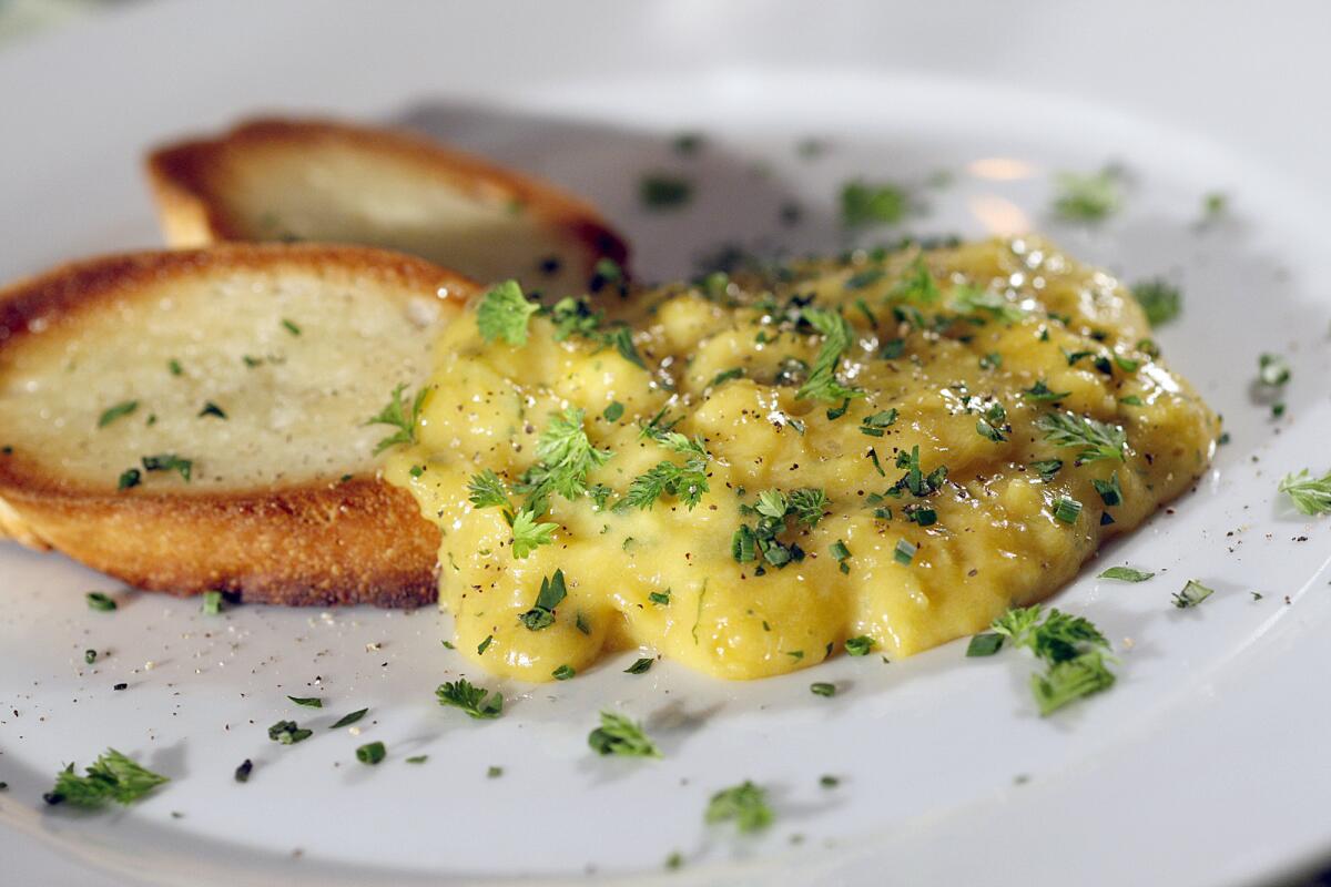 Creamy scrambled eggs sprinkled with chopped herbs, served with toasted rounds of bread