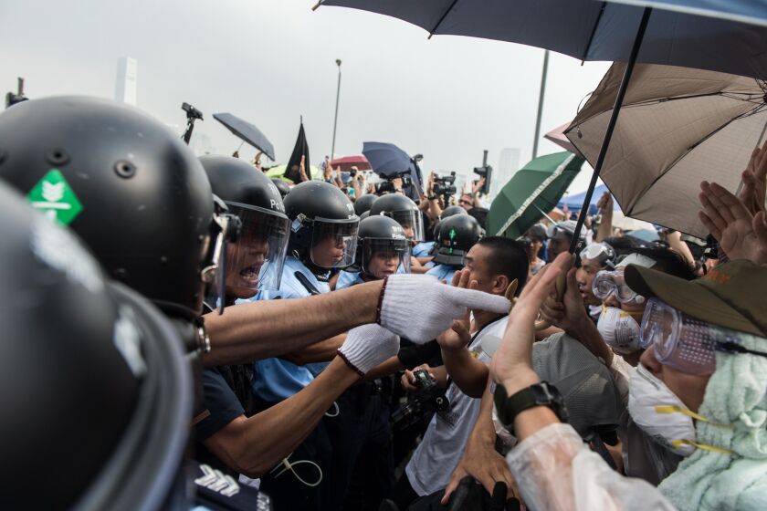 Police form a line to make way for an ambulance as pro-democracy protesters shout slogans outside the government headquarters in Hong Kong on Oct. 3.