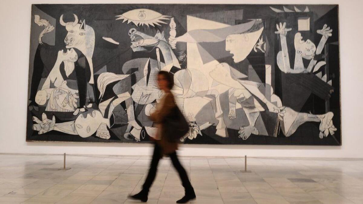 A woman walks by Pablo Picasso's "Guernica" at the Museo Reina Sofia in Madrid, Spain, in 2017.