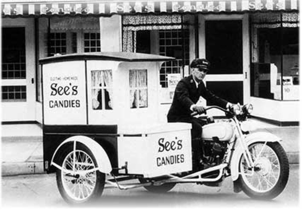 A black and white photograph of a See's Candies delivery motorcycle