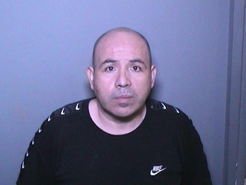 Booking photo of man with buzzed hair wearing black t-shirt with Nike logo.