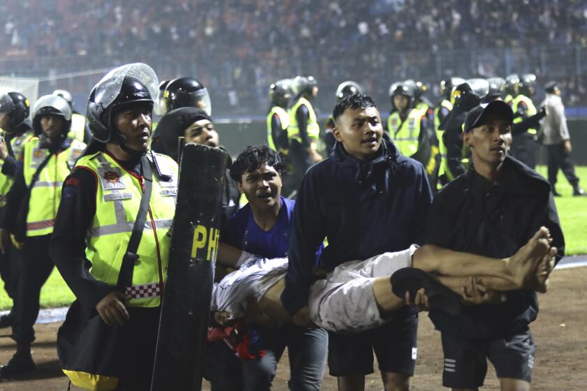 Soccer fans carry an injured man after clashes during a match at Kanjuruhan Stadium in Malang, Indonesia, on Oct. 1, 2022.