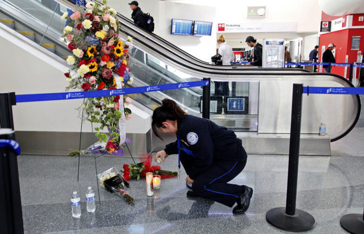 Transportation Security Administration officer Alexa Mendoza lights a candle at a memorial to TSA officers killed and wounded at Terminal 3 at Los Angeles International Airport.