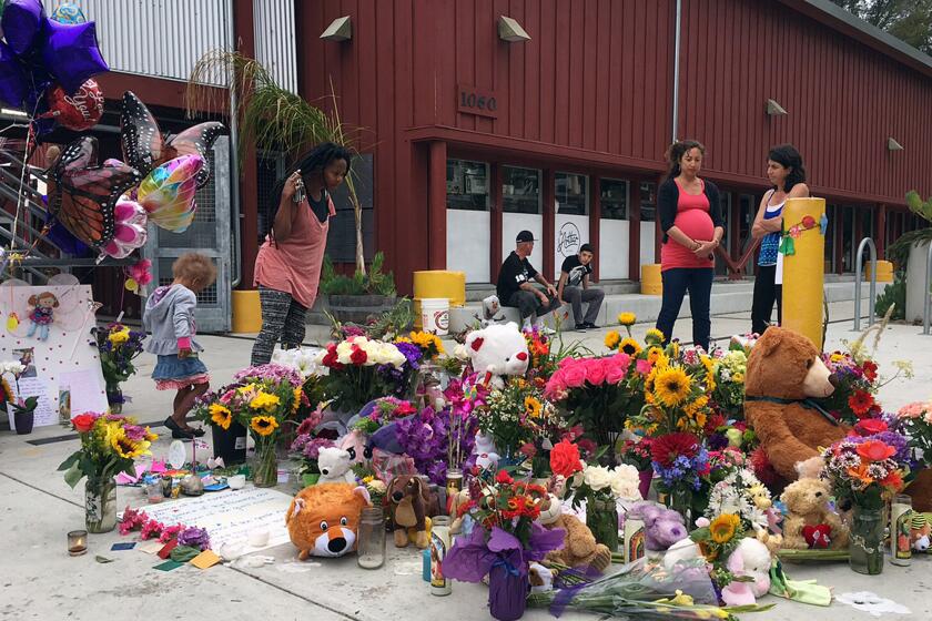 Neighbors look at the growing memorial of flowers, stuffed animals and notes left in memory of Madyson Middleton in Santa Cruz, Calif., Wednesday, July 29, 2015. The close-knit community of artists in Northern California are grieving the death of the 8-year-old girl whose body was found in a trash bin at their housing complex and expressed shock that one of their own, a teenage boy, has been arrested in her death. (AP Photo/Terry Chea)