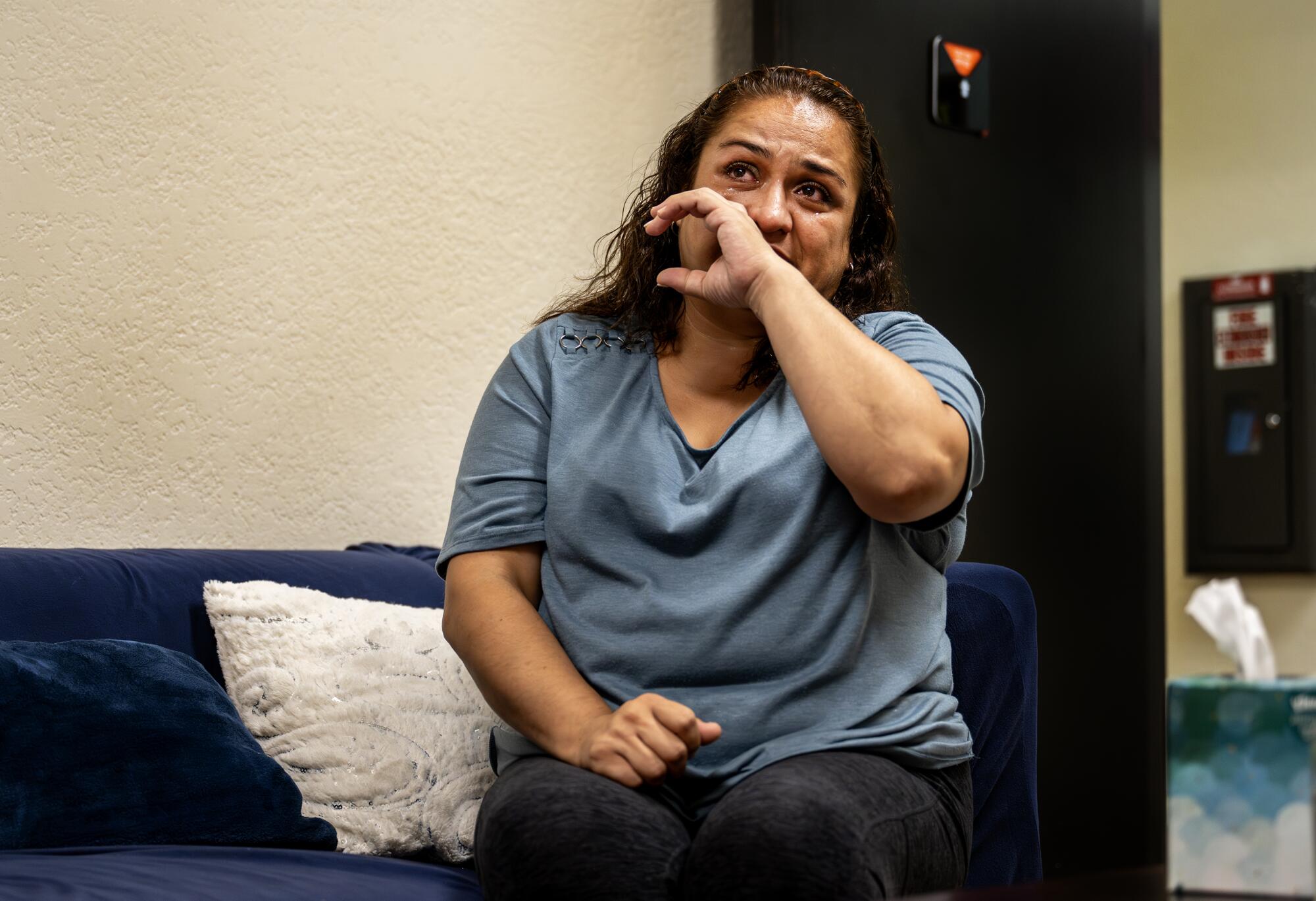 Nerry Montes is brought to tears as she sits on a couch.