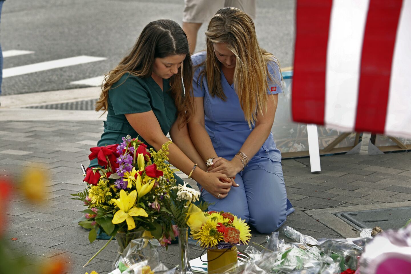 Sarah Roemer, left, and Brandi Van Dongen, nurses at Arnold Palmer Childrens Hospital in Orlando, pray at one of the memorials.