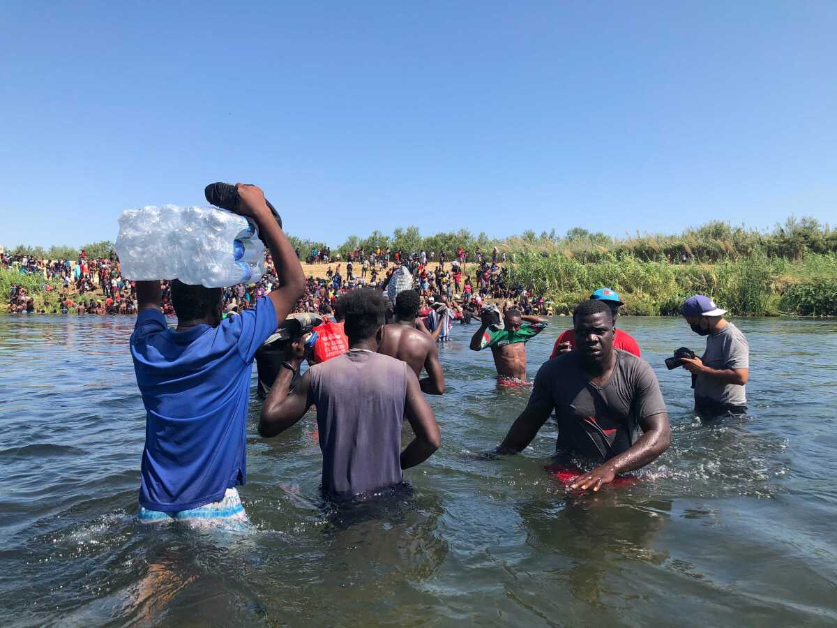 El migrante haitiano Junior Desterville, centro, cruza el Río Grande