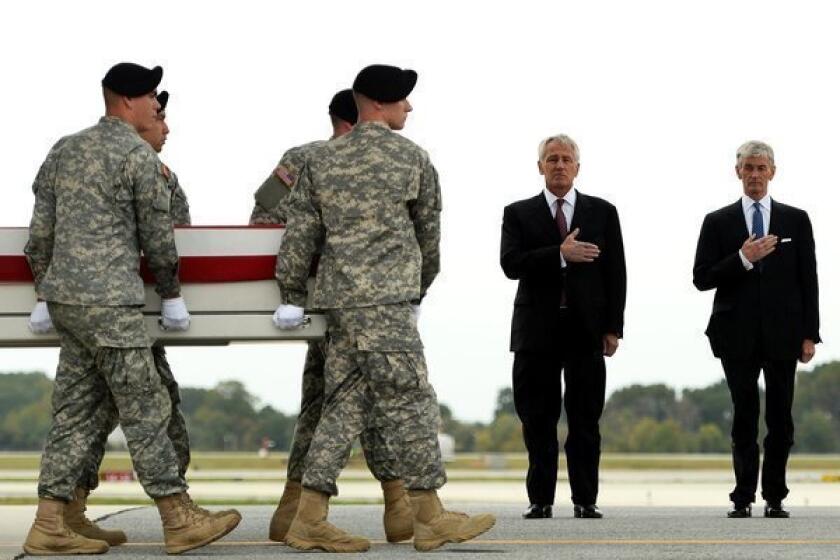 Secretary of Defense Chuck Hagel and Secretary of the Army John McHugh stand by as soldiers carry the flag-draped transfer case containing the remains of U.S. Army Pfc. Cody J. Patterson at Dover Air Force Base.