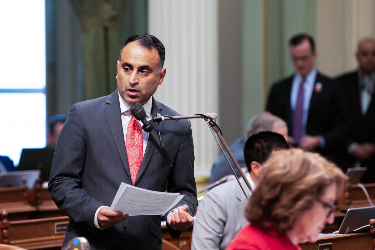 Assemblyman Ash Kalra holds documents while speaking into a microphone