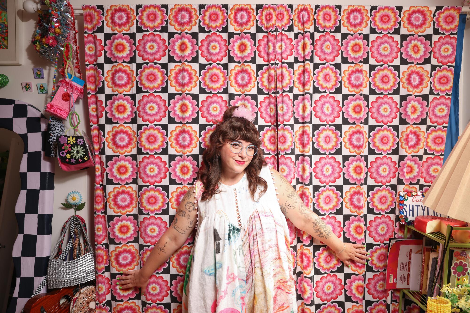 A portrait Sam Reece in her crafting studio, against a pink floral curtain.