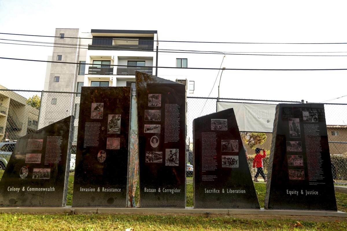 LOS ANGELES, CA - JANUARY 14, 2022 - - A child walks past the Filipino World War II monument at Lake Street Park in Historic Filipinotown in Los Angeles on January 14, 2022. (Genaro Molina / Los Angeles Times)