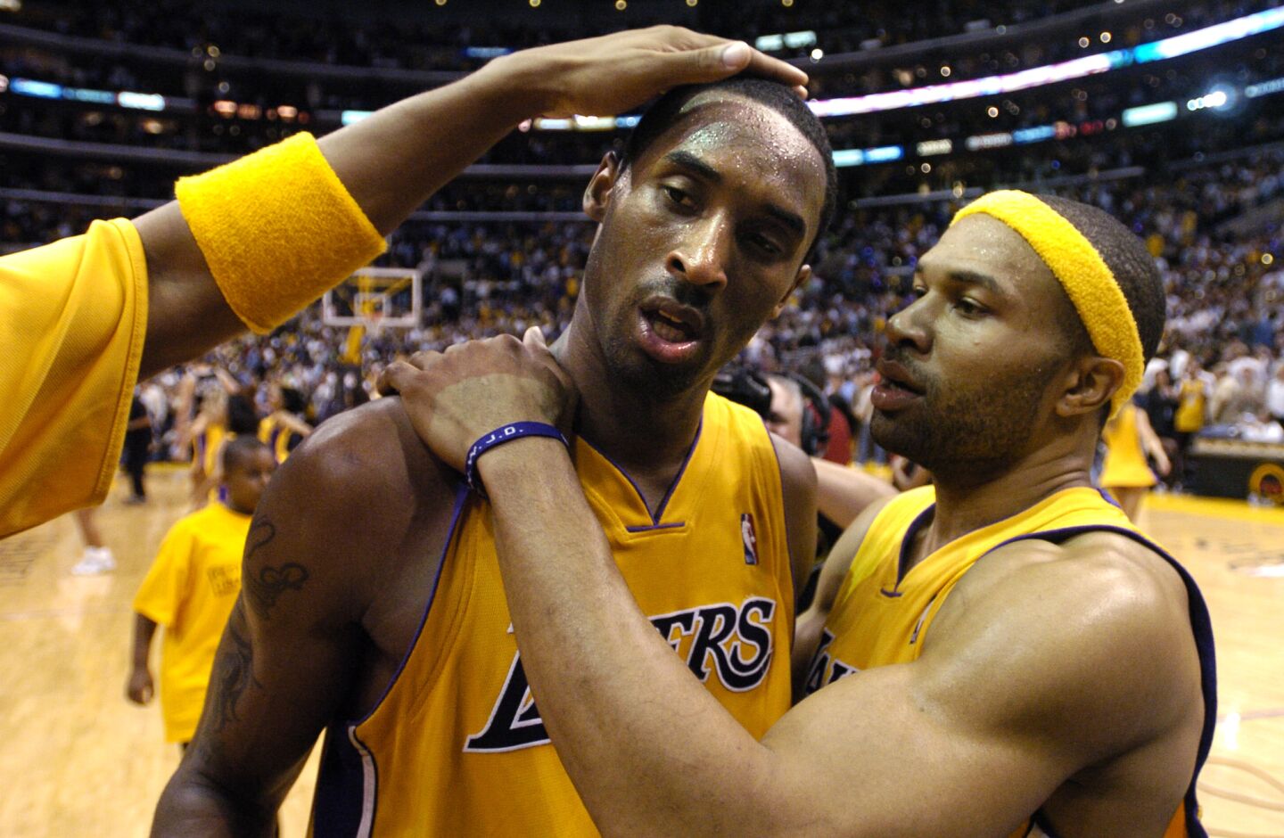 Derek Fisher puts his arms around Kobe Bryant while another Laker's hand can be seen atop Bryant's head.