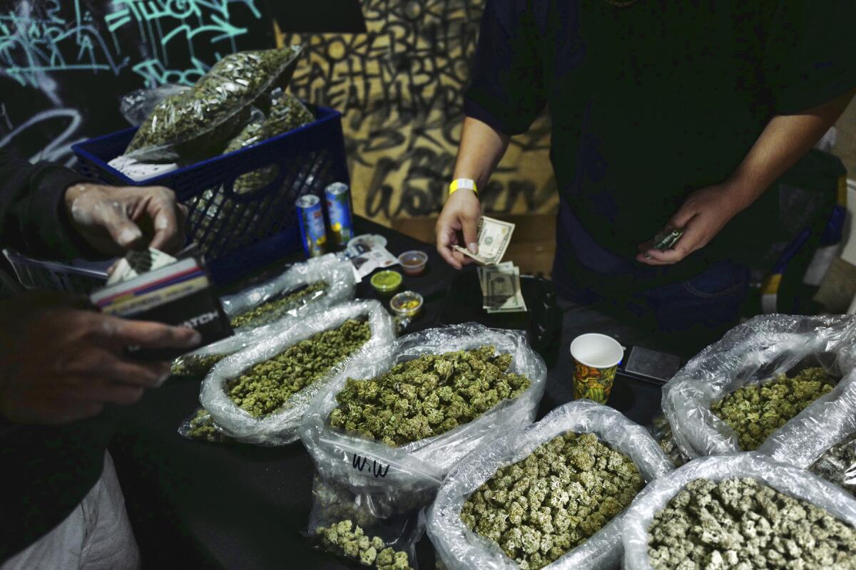 A vendor and customer exchange cash at a marijuana marketplace.