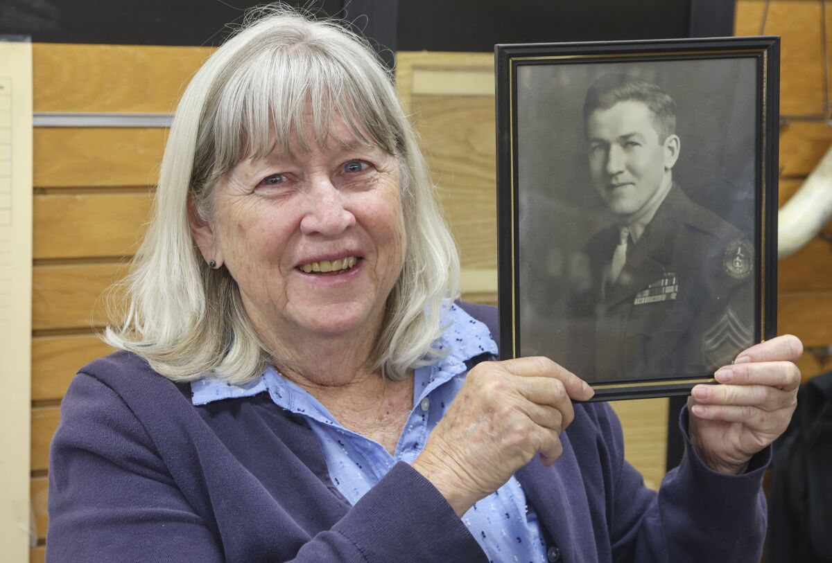 Sandy McQuillen holds up a military photo of her late father, Louis E. Duncan 