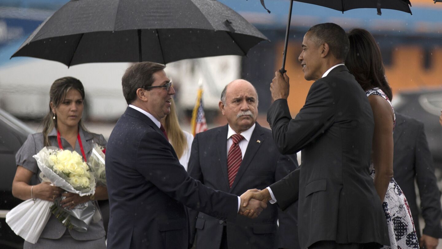 President Barack Obama shakes hands with Cuban Foreign Minister Bruno Rodriguez as First Lady Michelle Obama looks on upon arrival at the airport in Havana on Sunday.