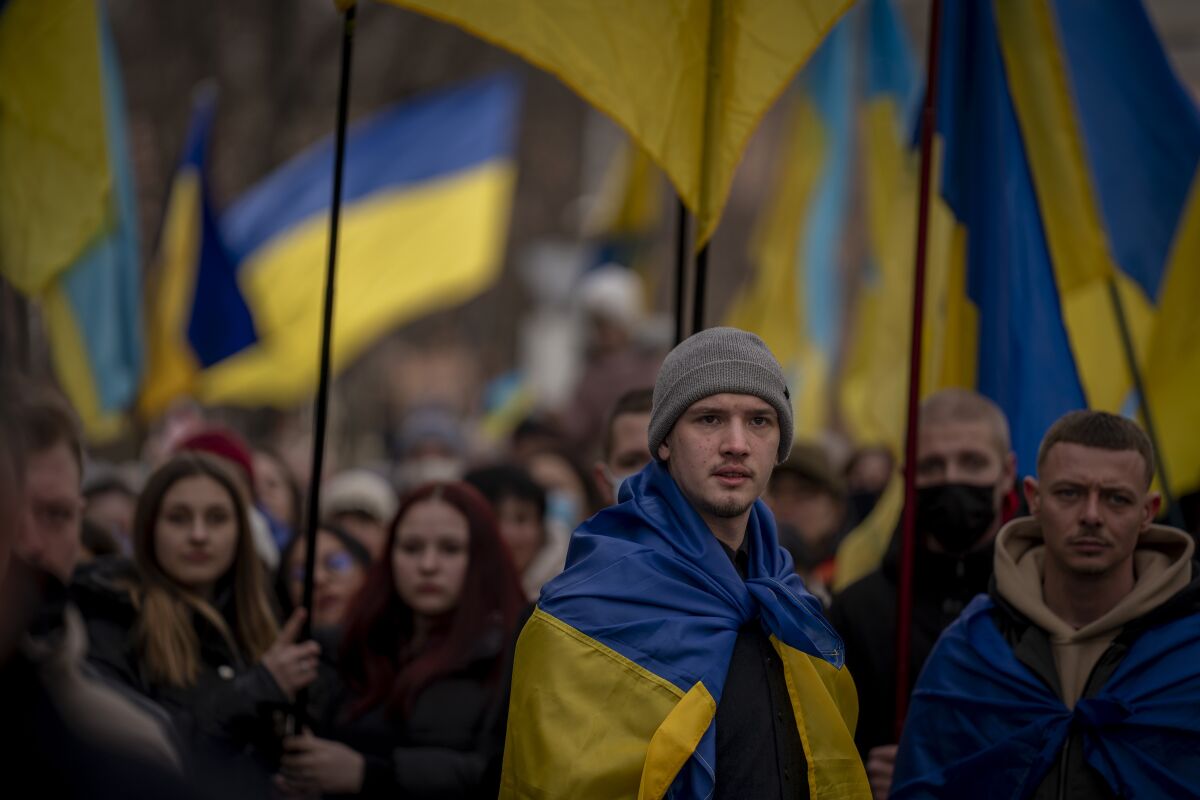 Demonstrators wear and carry Ukraine flags.