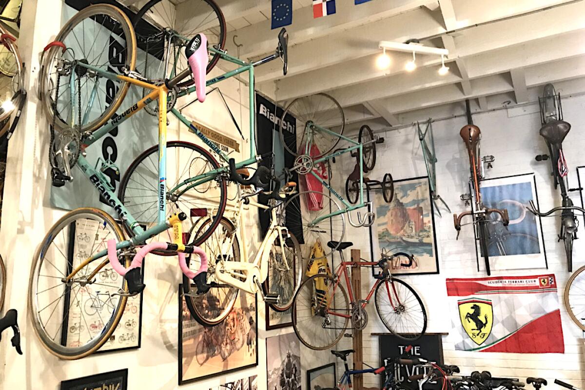 Bicycles hang on the white walls of a shop that's decorated with posters.