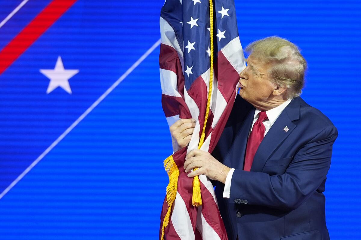 El candidato presidencial republicano, el expresidente Donald Trump, abraza y besa la bandera 