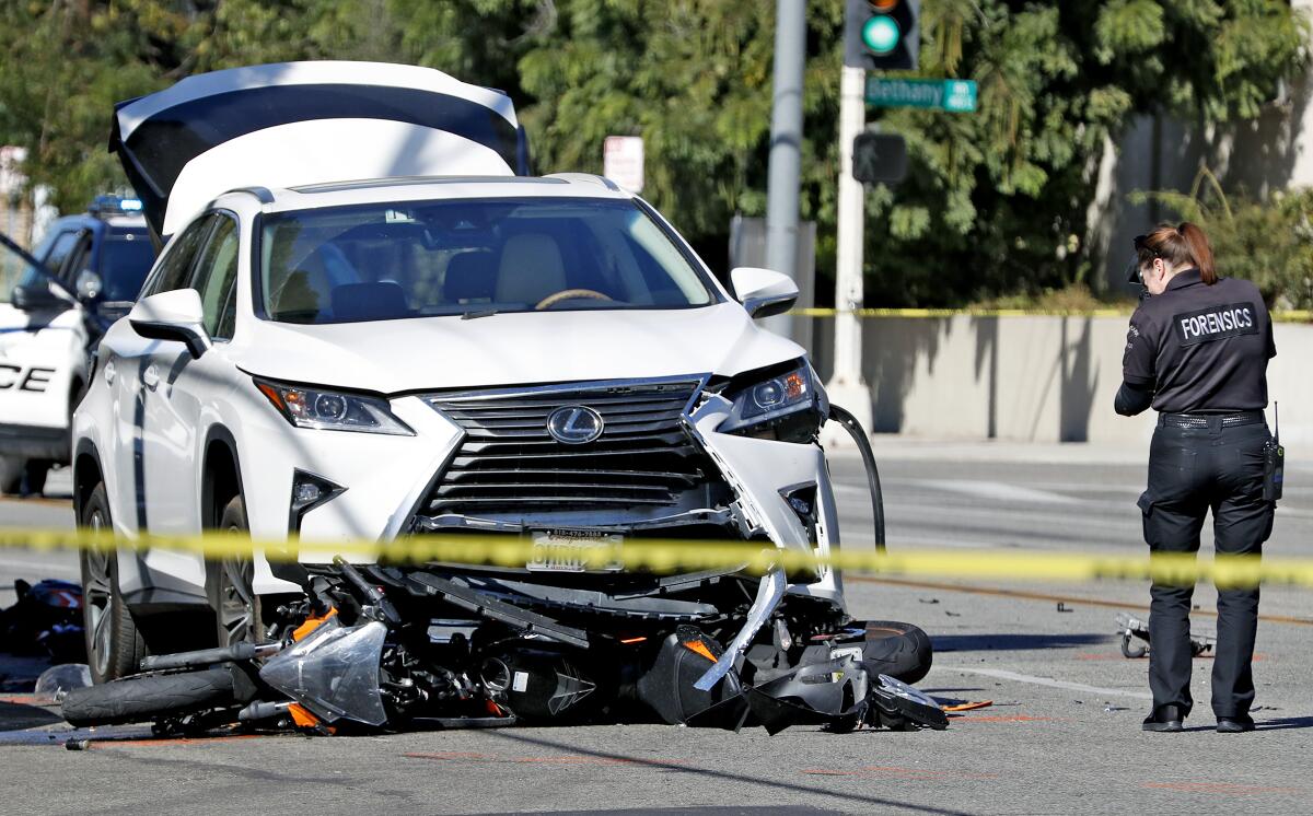 A Burbank police forensic investigator photographs the scene of a fatal collision between a vehicle and a motorcycle near the intersection of Glenoaks Boulevard and Cornell Drive on Thursday, Oct. 31, 2019.
