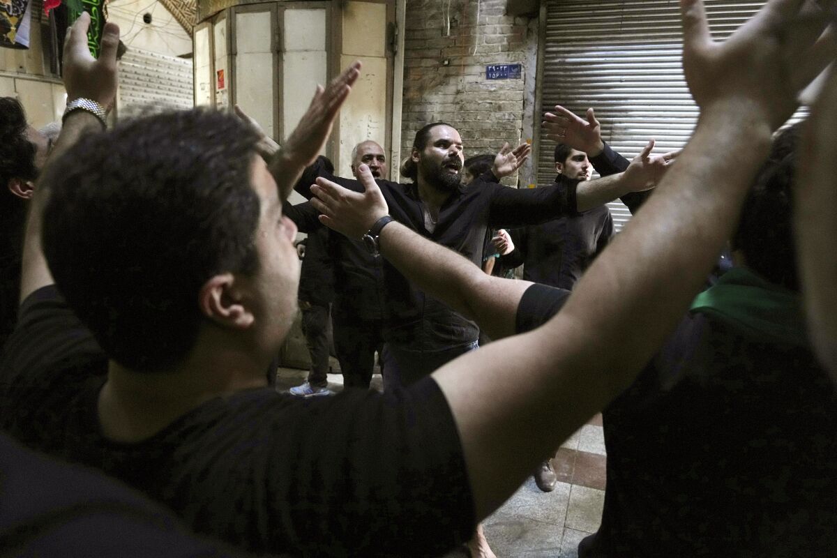 Men in black lift their arms to the sky.