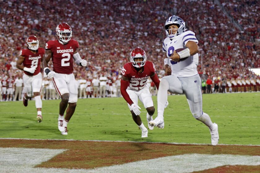 Kansas State quarterback Adrian Martinez (9) carries the ball for a touchdown past Oklahoma defensive lineman Jonah Laulu (8), left, linebacker David Ugwoegbu (2) and defensive back Justin Broiles (25) in the first half of an NCAA college football game, Saturday, Sept. 24, 2022, in Norman, Okla. (AP Photo/Nate Billings)