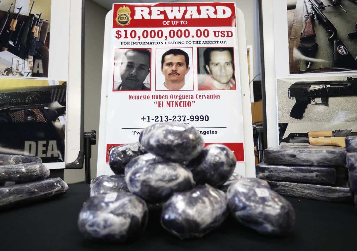 A poster of wanted suspects hangs on a wall in an office where bags of confiscated methamphetamine sit on a table