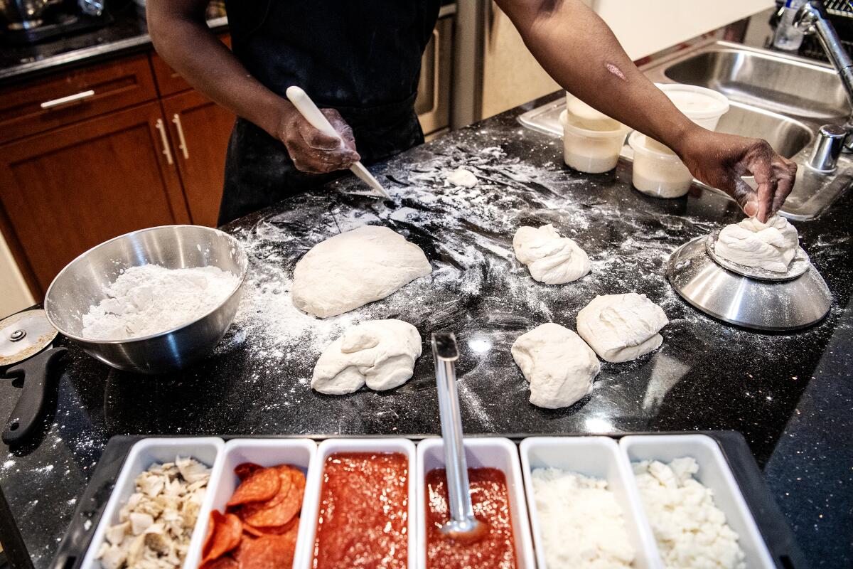 Pizza dough and toppings on a flour-covered countertop. 