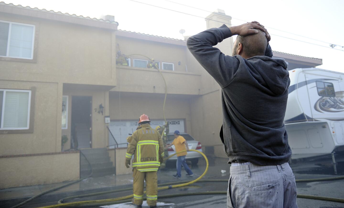 A resident watches the roof of his house burn as firefighters battle the blaze on North Marshall Court in San Pedro on Friday.