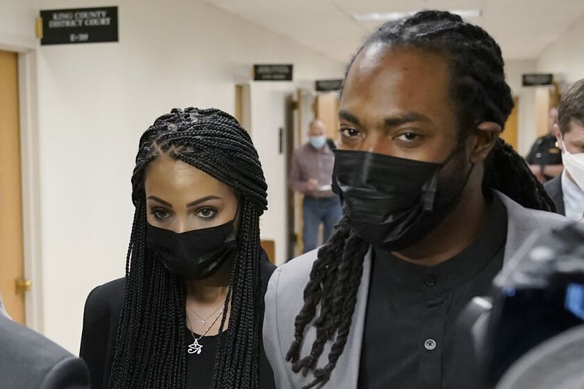 Richard Sherman, right, walks with his wife Ashley, Friday, July 16, 2021, following a King County District Court hearing in Seattle. The NFL football cornerback, who has played with the Seattle Seahawks and the San Francisco 49ers, was arraigned on five criminal charges Friday after he was arrested Wednesday after police said he crashed his car in a construction zone along a busy highway east of Seattle and then tried to break into his in-laws' home in the suburb of Redmond, Wash. (AP Photo/Ted S. Warren)