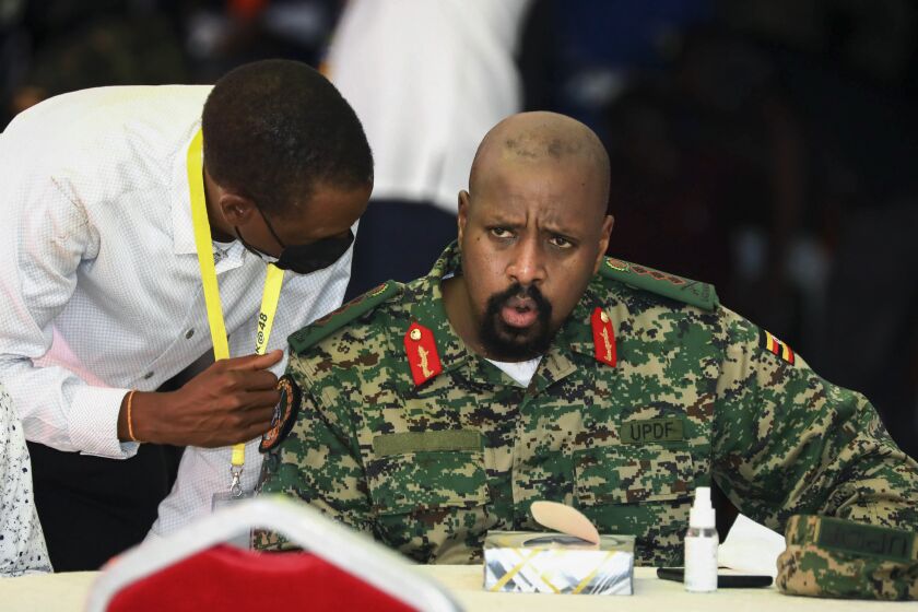 FILE - Then Lt. Gen. Muhoozi Kainerugaba, right, son of Uganda's President Yoweri Museveni, speaks to Attorney General Kiryowa Kiwanuka, left, at a "thanksgiving" ceremony in Entebbe, Uganda on May 7, 2022. Uganda's President Yoweri Museveni fired his son Muhoozi Kainerugaba as commander of the nation's infantry forces Tuesday, Oct. 4, 2022 after the son tweeted an unprovoked threat to capture the capital of neighboring Kenya, drawing widespread concern in East Africa. (AP Photo/Hajarah Nalwadda, File)