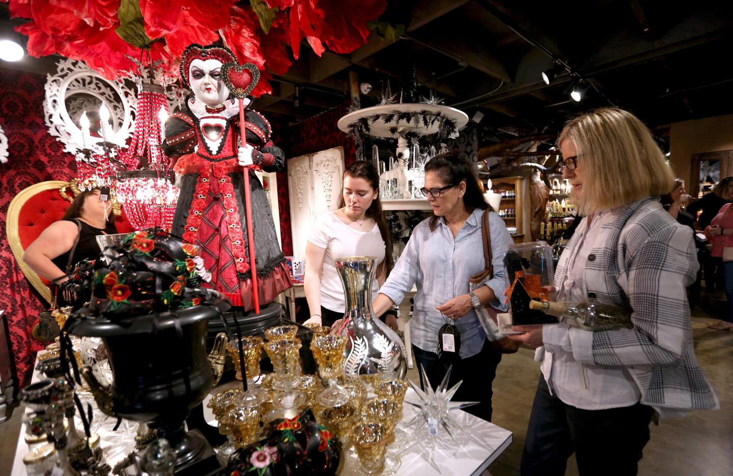 From left, Kate and Cynthia Evans, both of Laguna Niguel, and Karen Nixon of Irvine browse items at the Queen of Hearts display during a preview of Roger's Gardens' "Malice in Wonderland" Halloween boutique, which opens to the public Friday.
