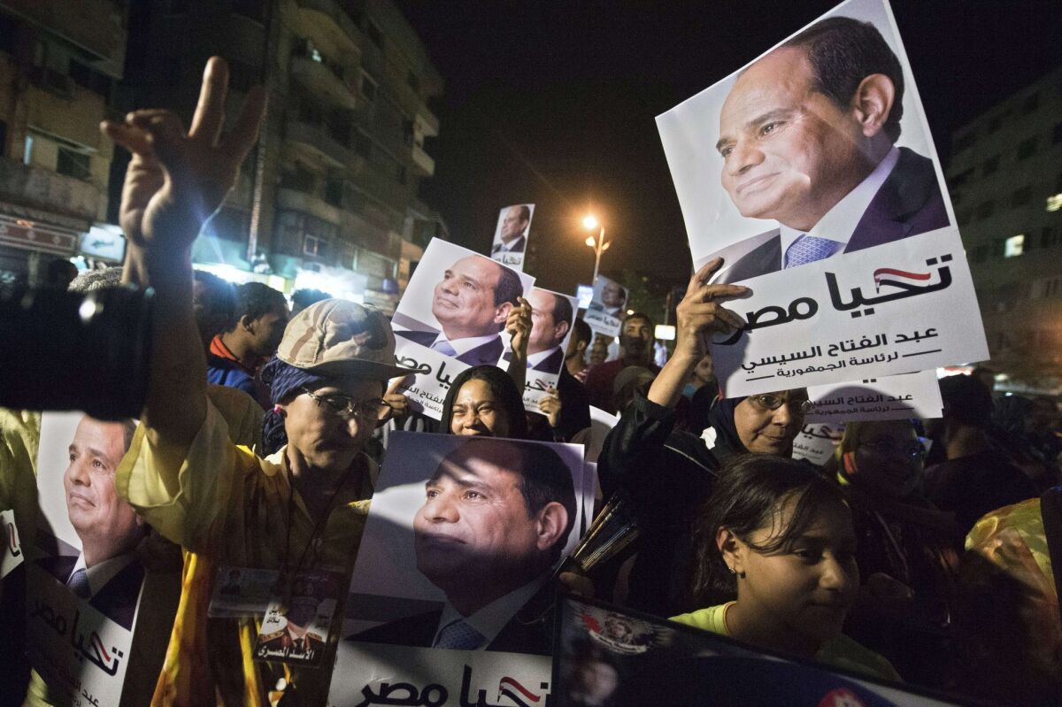 Supporters of Egyptian presidential candidate Abdel Fattah Sisi hold signs as they watch him on a screen during his first television interview.