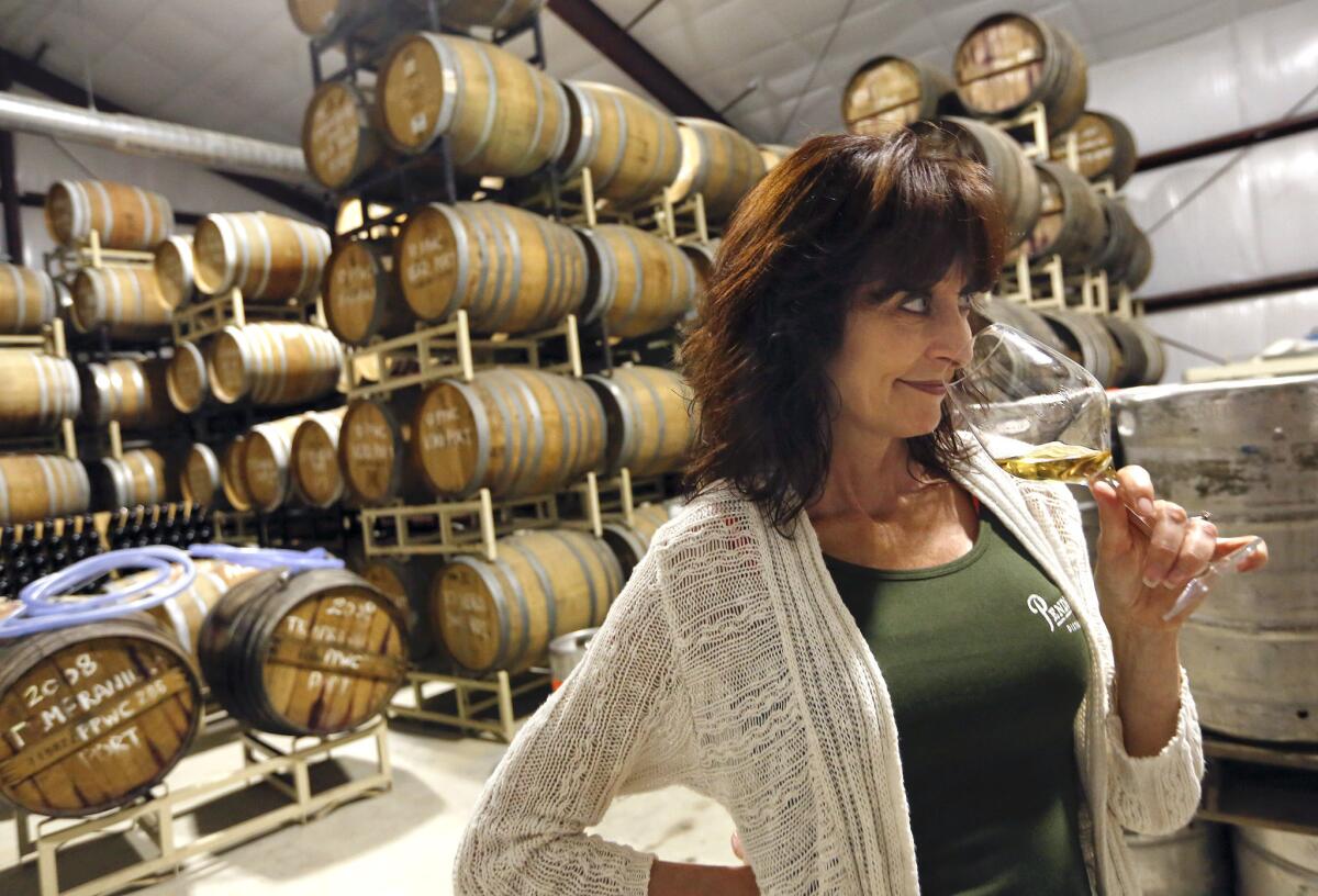 Lola Glossner, owner of Pendray's Distillery in Templeton, Calif., just south of Paso Robles, checks the aroma from a glass of nebbiolo brandy inside the storage warehouse.