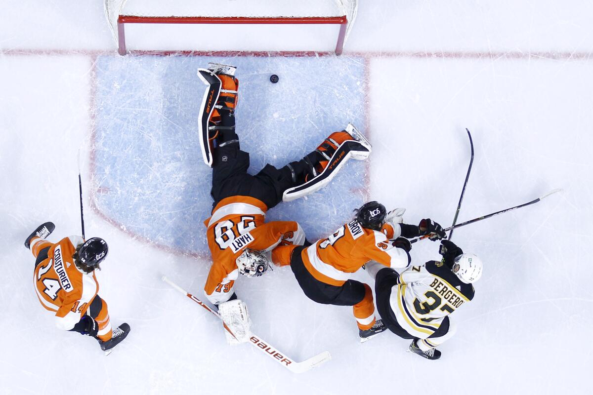 Boston Bruins' Patrice Bergeron, right, scores a goal past Philadelphia Flyers goaltender Carter Hart (79) as Ivan Provorov (9) and Sean Couturier (14) defend during the first period of an NHL hockey game, Tuesday, April 6, 2021, in Philadelphia. (AP Photo/Derik Hamilton)