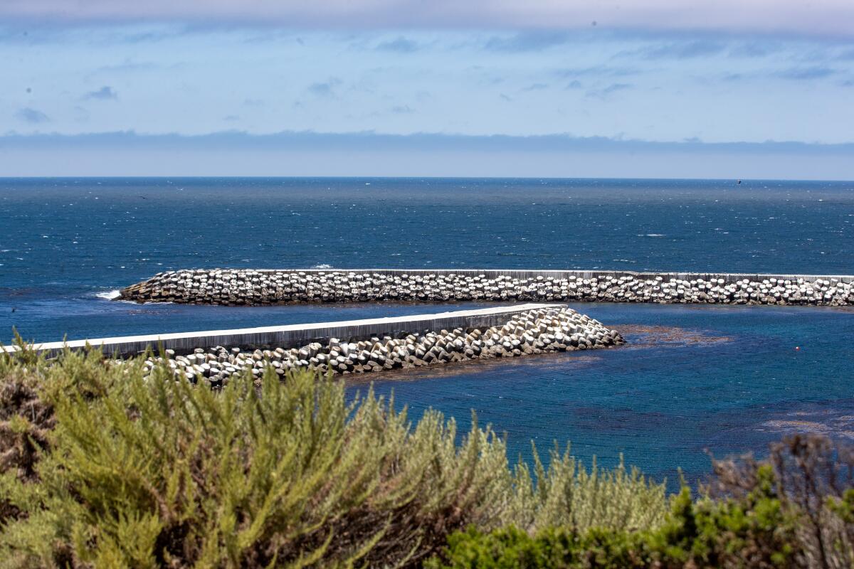 A view of the ocean from the shore, showing built structures in the water that block waves.