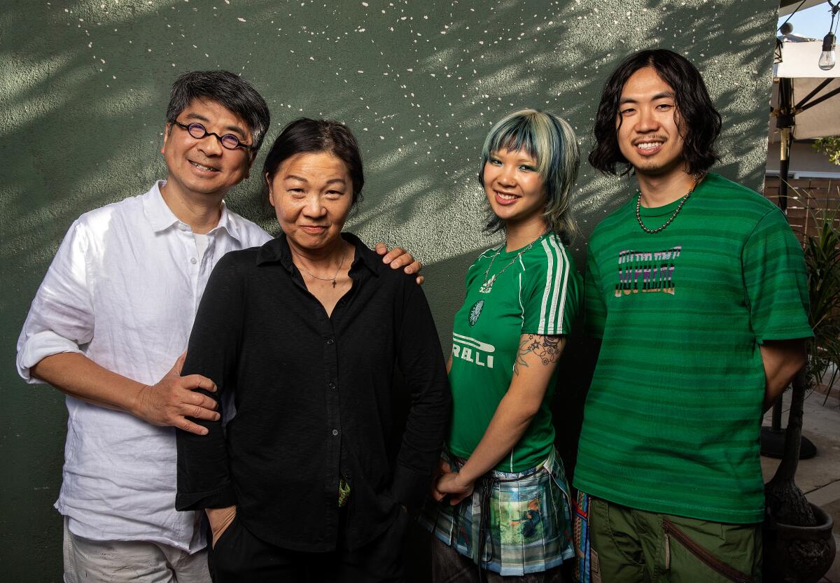 Olive Yu and Adrian Yu pose with their parents, Garson and Irene Yu, in front of a green wall.