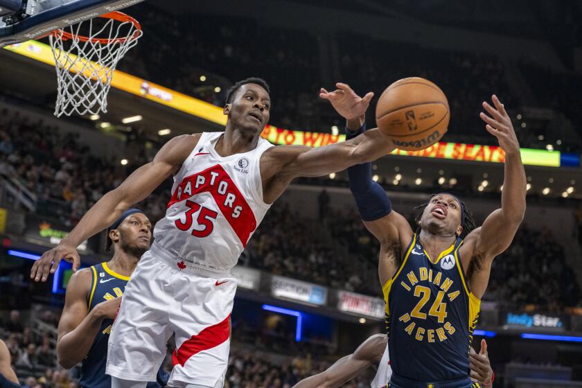 Toronto Raptors center Christian Koloko (35) reaches for the ball as he battles Indiana Pacers guard Buddy Hield (24) for a rebound during the first half of an NBA basketball game in Indianapolis, Monday, Jan. 2, 2023. (AP Photo/Doug McSchooler)