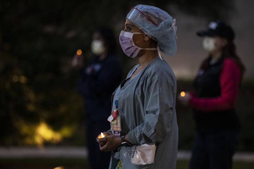 ORANGE, CA, APRIL 20 - Nurse anesthetist Nilu Patel quietly stands with fellow nurses at UC Irvine Medical Center for an hourlong candlelight vigil at their shift change to describe conditions and the need for more N95 respirators and protective gear required to safely treat coronavirus patients. The vigil is organized by the California Nurses Association and National Nurses United unions. (Robert Gauthier / Los Angeles Times)