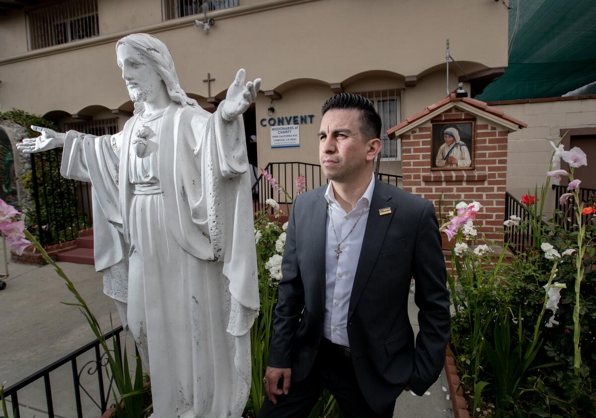 A man stands next to a religious statue at a church.