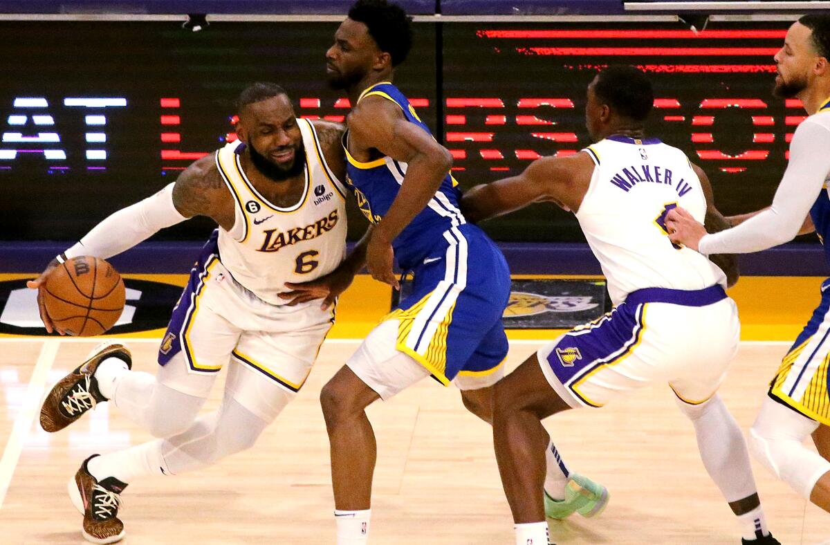 Lakers star LeBron James uses a screen by teammate Lonnie Walker IV while driving against Warriors forward Andrew Wiggins.