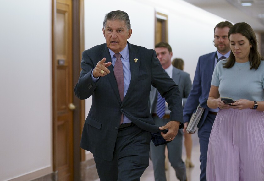 Man in a suit pointing and walking through a hallway