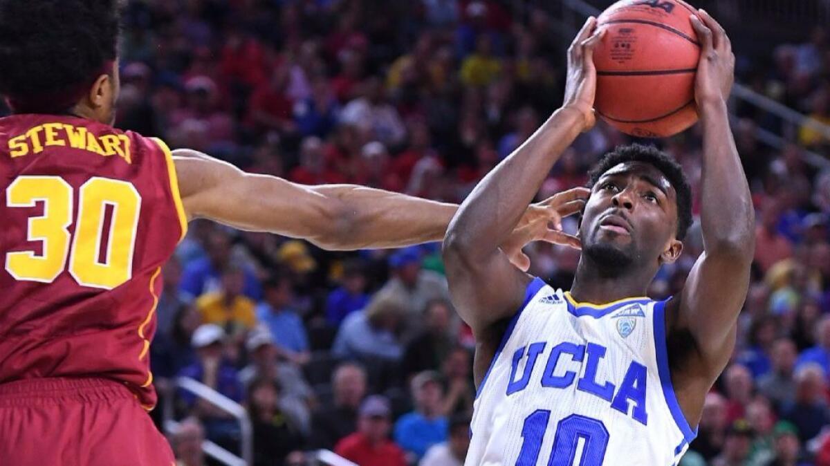 UCLA guard Isaac Hamilton gets a hand to the face from USC's Elijah Stewart while driving to the basket during the Pac-12 Conference tournament.